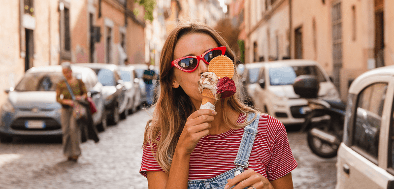 Woman eating ice cream at a tourist spot on her trip.